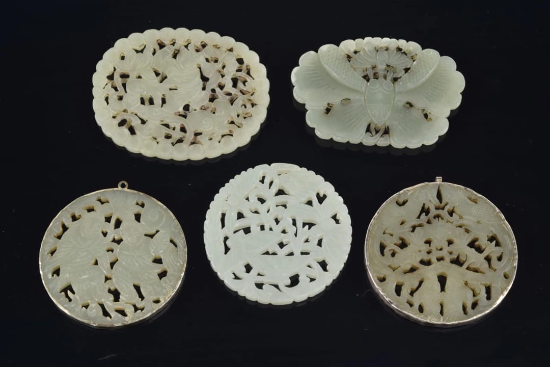 4 jade pendants. China. 19th to early 20th century. One silver mounted. 3in.