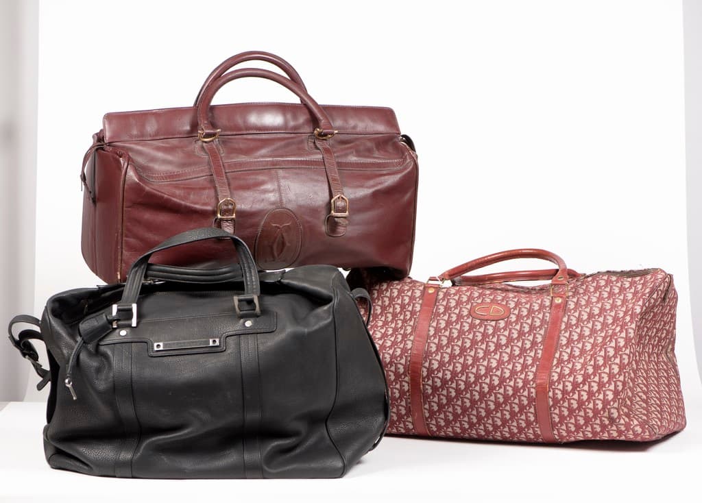 Trois bagages : 1/ CARTIER. Sac de voyage en cuir de couleur bordeaux