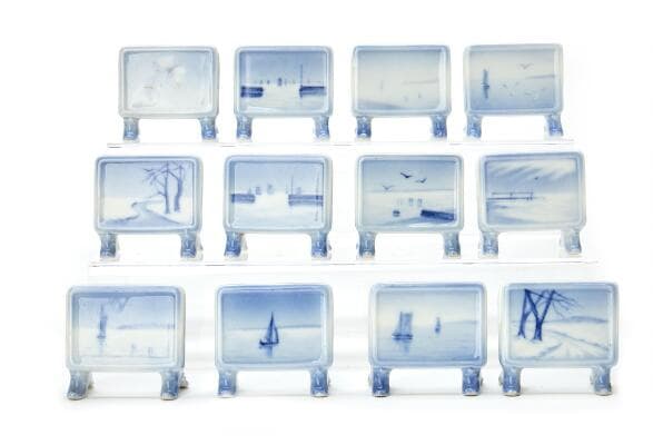 12 porcelain place card holders, decorated in blue. Each H. 6 cm W.
