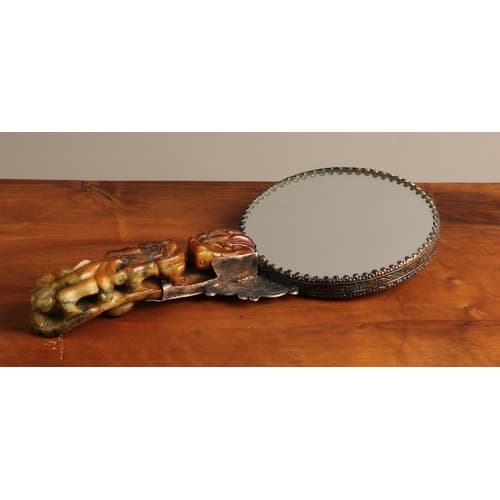 A Chinese white metal hand mirror, chased to verso with a dr...