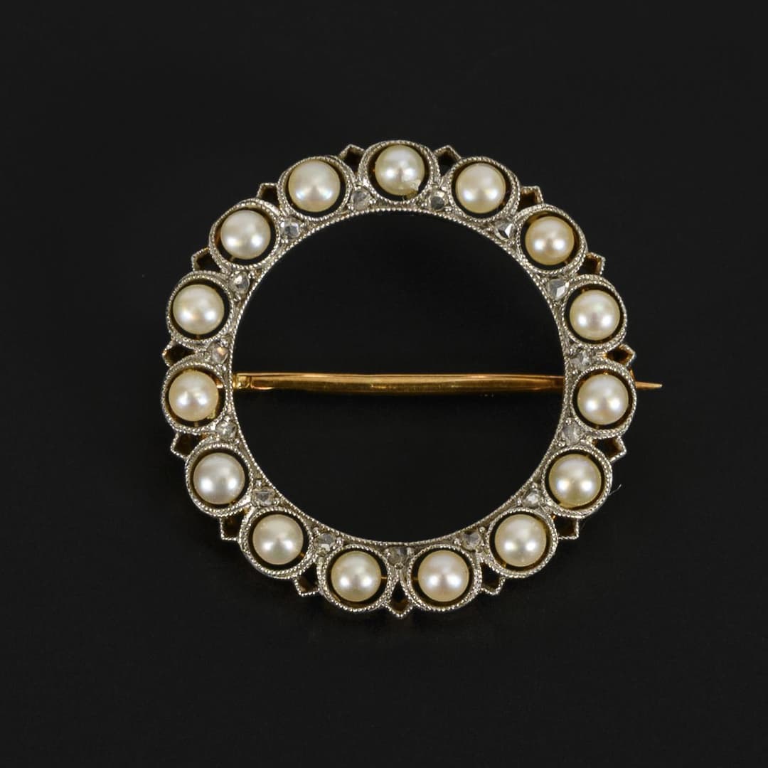 Small, round brooch set with pearls and diamonds.